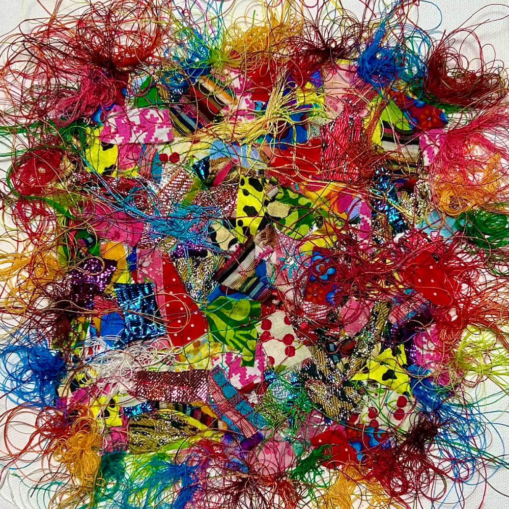Tableau avec un patchwork de chutes de tissus multicolores composées de motifs variés ainsi que de fils multicolores 100 % coton entremêlés qui débordent en volutes hors du patchwork, orné de quelques sequins sur le dessus de l’oeuvre
